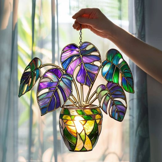 This stained glass piece shows off a Monstera plant with glowing purple and green leaves, giving off a super artistic vibe!